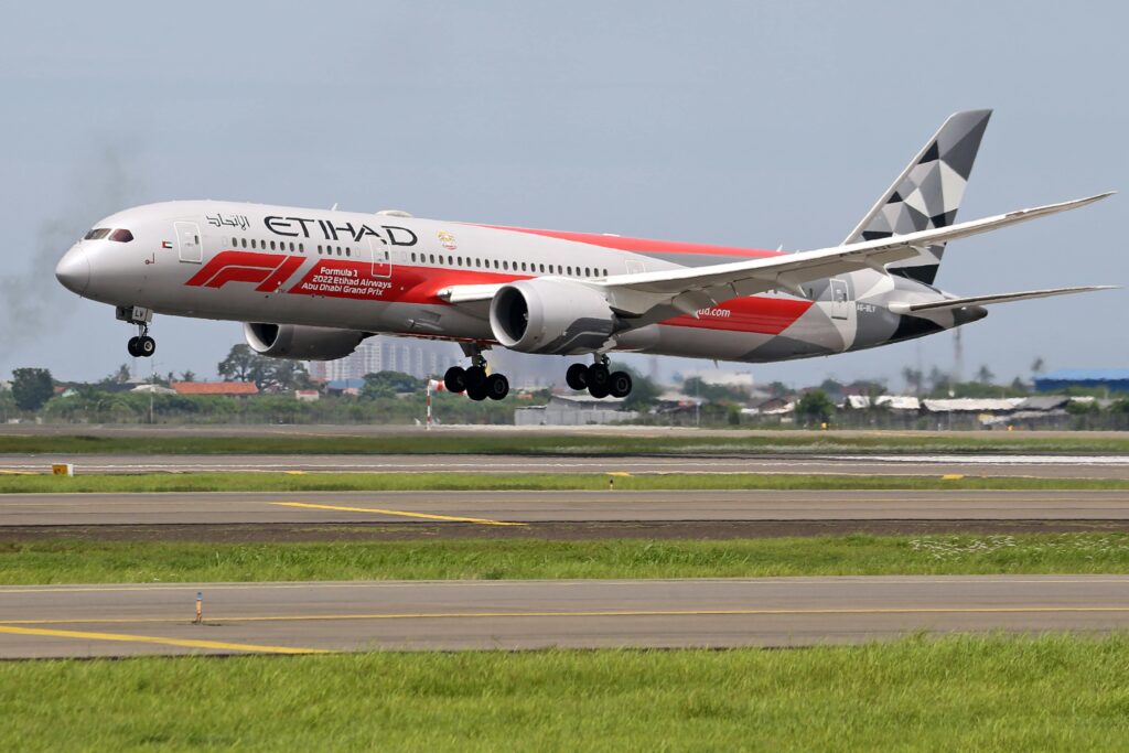 Etihad Airways Boeing 787 Dreamliner landing on runway at an airport with Formula 1 livery.