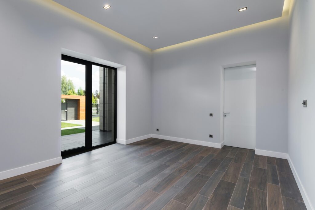 pexels-photo-7031619-7031619 Spacious and modern empty room with wooden floors and large windows overlooking a garden.